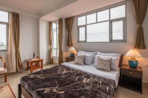 1 dormitorio con 1 cama grande y 2 ventanas en StayVista's Mystic Nest - Mountain & Valley-View Apartment with Contemporary Interiors & Modern Amenities, en Gangtok