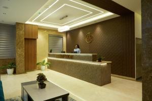 a woman standing at a reception desk in a lobby at VOVO PREMIER HOTEL in Bangalore