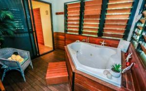 a large bathroom with a tub and a chair at Sunbird Gardens Villa 3 in Agnes Water