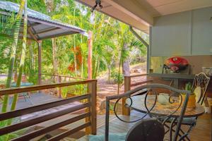 a room with a balcony with a table at Sunbird Gardens Villa 3 in Agnes Water
