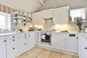 a white kitchen with white cabinets and appliances at Jasmine Cottage, Upper Slaughter, Cotswolds in Cheltenham +44 photos