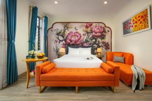 a bedroom with a bed and an orange chair at The Sono Hanoi Hotel in Hanoi