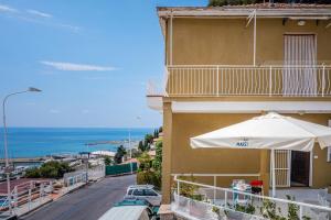 a balcony of a building with an umbrella and a street at Casa stella in San Lorenzo al Mare
