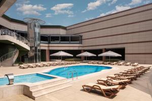 a pool in front of a building with chairs and umbrellas at Grand Cevahir Hotel Convention Center in Istanbul