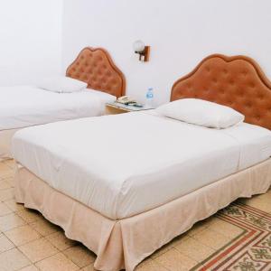 JomblangにあるHotel Candi Baruのベッドルーム1室(白いシーツが備わるベッド2台付)