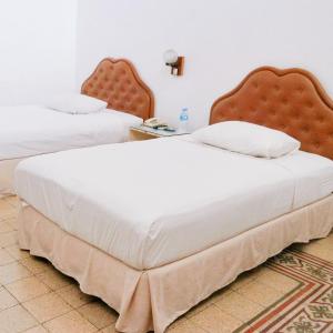 a bedroom with two beds with white sheets at Hotel Candi Baru in Jomblang