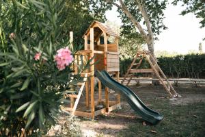 um parque infantil de madeira com um escorrega e uma estrutura de brincar em Mas du Versadou, dans un espace naturel protégé, piscine Chauffée, Spa et salle de jeux em Saint-Gilles