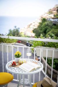 a table with a book and a glass of wine on a balcony at House on the rock in Positano