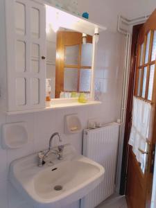 ein weißes Badezimmer mit einem Waschbecken und einem Spiegel in der Unterkunft Explore Aegina Island in Souvala
