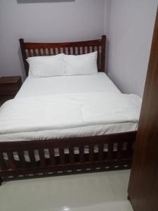 a bed with a wooden frame and white sheets at Tulsi Inn at Walking Street in Pattaya South