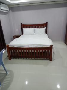 a bedroom with a bed with white sheets and a blue chair at Tulsi Inn at Walking Street in Pattaya South