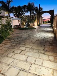 a stone driveway with an arch and palm trees at Villa Casole Short Lets in Copertino