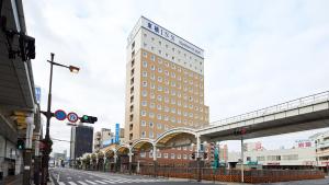 een hoog gebouw in een stadsstraat met een brug bij Toyoko Inn Iwakuni eki Nishi guchi in Iwakuni