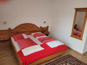 a bedroom with a bed with a red blanket and a mirror at Waldpension in Regenstauf