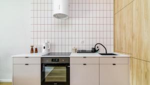 a kitchen with white cabinets and a sink and an oven at InTheMiddle in Ostróda