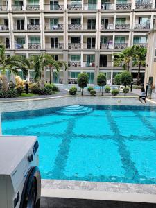 a large blue swimming pool in front of a building at Pretty nice pool view一楼泳池景观房 in Jomtien Beach