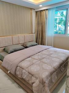 a large bed in a bedroom with a window at Pretty nice pool view一楼泳池景观房 in Jomtien Beach