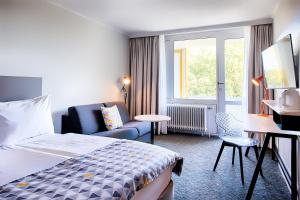 um quarto de hotel com uma cama e uma cadeira e uma janela em Holiday Inn Munich - South, an IHG Hotel em Munique