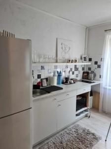 a white kitchen with a sink and a refrigerator at Dviejų kambarių butas in Kaunas