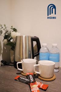 a counter with two cups and a kettle and water bottles at Homi Breeze 和逸微风 in Kota Kinabalu