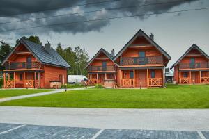 a group of wooden houses on a green field at Siedlisko Malechowo in Ustronie Morskie