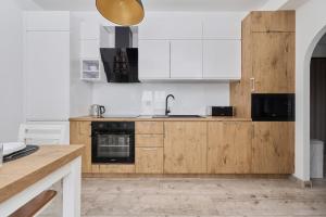 una cocina con electrodomésticos blancos y armarios de madera en Spacious Apartment suitable for Remote Work with Balcony & Parking by Renters, en Wroclaw