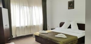 een slaapkamer met 2 handdoeken op een bed met een raam bij Pensiunea Magnolia din Tismana in Tismana
