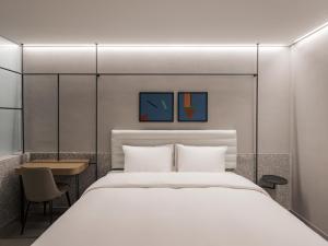 - une chambre avec un grand lit blanc et une table dans l'établissement Ramada Plaza by Wyndham Chungjang, à Gwangju
