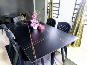 a black dining room table with black chairs and flowers at Qairissa Homestay Kuantan in Kuantan