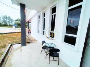 a table and two chairs on the porch of a building at Qairissa Homestay Kuantan in Kuantan