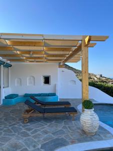 um pátio com uma pérgola de madeira e almofadas azuis em Seafront Villa Polyxene em Keratea