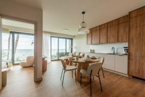 a kitchen and dining room with a table and chairs at Luksusowy Apartament Sun Seasons 24 w Rewalu z Widokiem, Basenem, Siłownią i Sauną by Noclegi Renters in Rewal