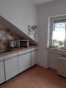 a kitchen with white cabinets and a sink and a window at Ferienwohnung Steinfeld in Konz