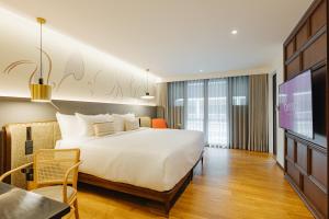 um quarto de hotel com uma cama e uma televisão em Hotel Sensai Nimman Chiang Mai - Adults Only em Chiang Mai