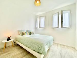 a white bedroom with a bed and two windows at Le Panoramic - Grand Balcon - Wifi Fibre - NOUVEAU in Lorient