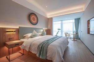 una camera da letto con un letto grande e una grande finestra di SSAW Boutique Hotel Zhijiang a Hangzhou