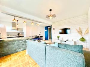 a living room with a blue couch and a kitchen at Le Panoramic - Grand Balcon - Wifi Fibre - NOUVEAU in Lorient +29 photos