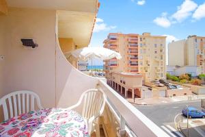 a balcony with a table and an umbrella and a city at Appartement Calme et Moderne avec vue mer 74 in Canet-en-Roussillon