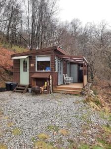 a small house with a porch and a deck at Yn Y Coed Tanyrallt in Llanybyther