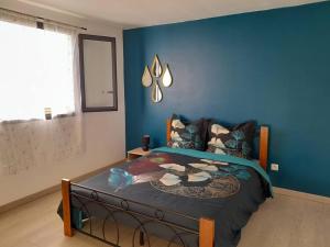 Schlafzimmer mit einem Bett mit blauer Wand in der Unterkunft Maison de vacances Leu ti coin des ô in Saint-Leu