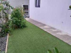 un jardín con césped verde al lado de una casa en Maison de vacances Leu ti coin des ô en Saint-Leu