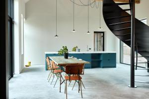 een eetkamer met een tafel en stoelen en een trap bij Suvelfabryk in Lioessens