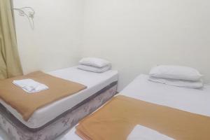 two twin beds in a small room with towels at Hotel Malang near Alun Alun Malang RedPartner in Malang