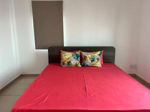 ein rotes Bett mit zwei Kissen in einem Zimmer in der Unterkunft Green Village Duplex in Grand-Gaube