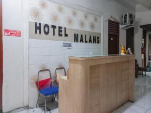 Hotel Malang near Alun Alun Malang RedPartner في مالانغ: علامة الفندق على جدار مع كرسيين