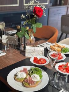 een tafel met borden eten en een roos bij New Grey Residence Apartament in Târgu-Mureş