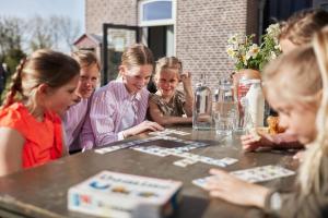 een groep mensen die aan een tafel zitten en een spel spelen bij Suvelfabryk in Lioessens