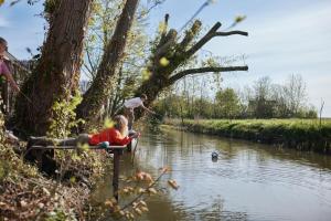 een man en een kind die vissen in een rivier bij Suvelfabryk in Lioessens