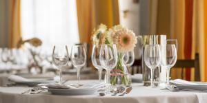 una mesa con copas de vino y un jarrón de flores en Nuevo Astur Spa en Sanxenxo