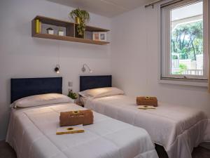 three beds in a room with a window at Rivaverde Family Camping Village in Marina di Ravenna